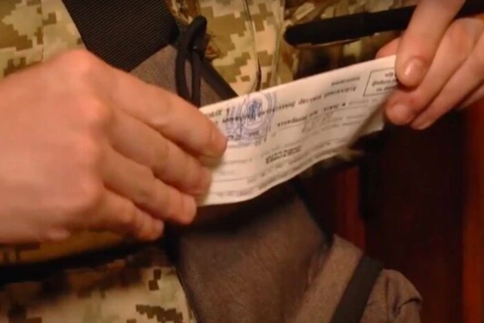 Військовий демонструє процес вручення повістки